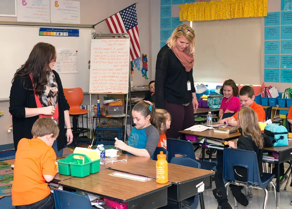 Two U N E education students teach children in an elementary school classroom